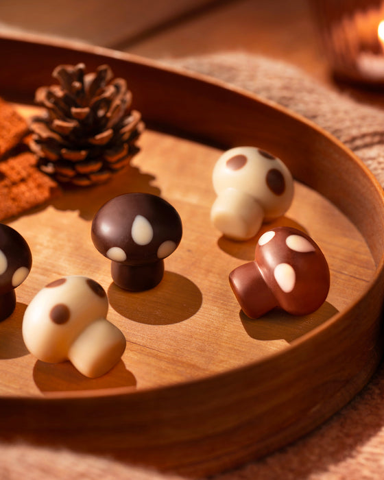Leonidas chocolate mushroom candies on a wooden tray with a warm glow.