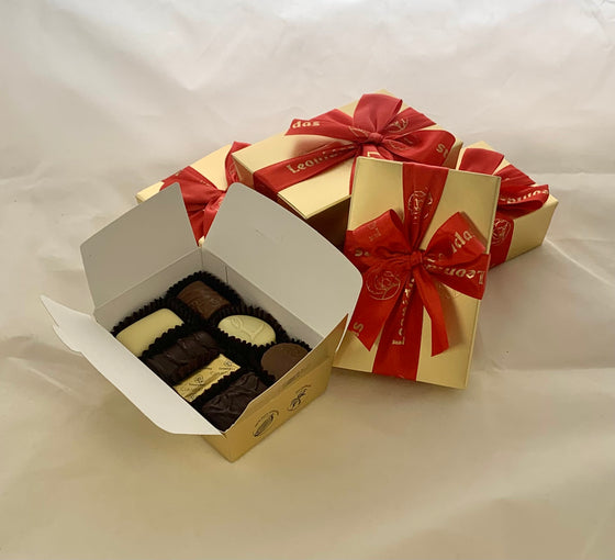 Set of five mini Leonidas ballotin giftboxes with red bows on a white background, containing assorted chocolates.