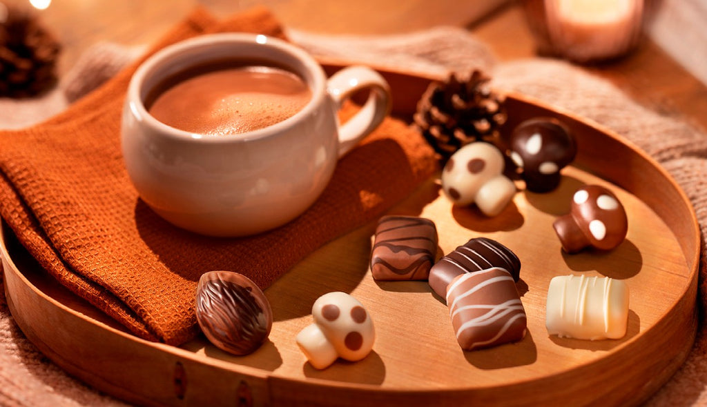Cup of coffee on a tray with a mix of milk, white, and dark Leonidas fall chocolates